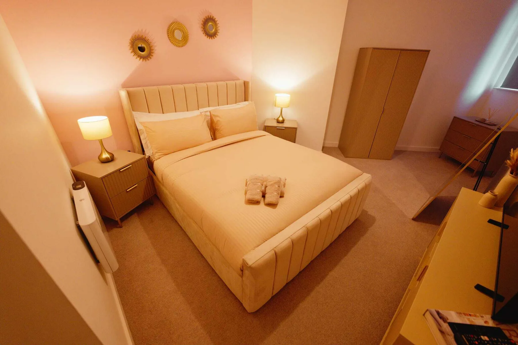Un dormitorio con una cama, mesitas de noche y un armario.