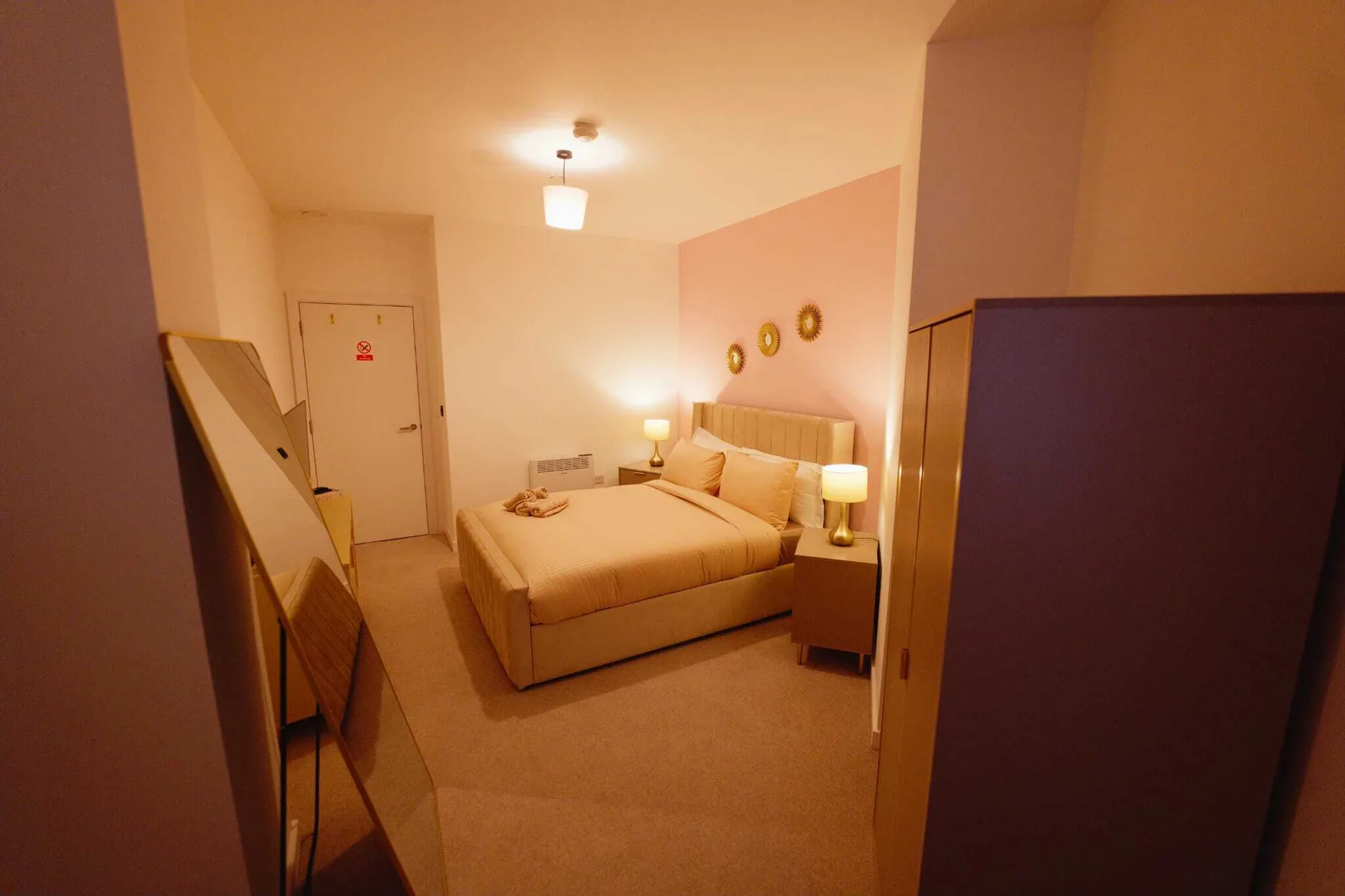 Dormitorio con cama, mesas de noche e iluminación cálida.