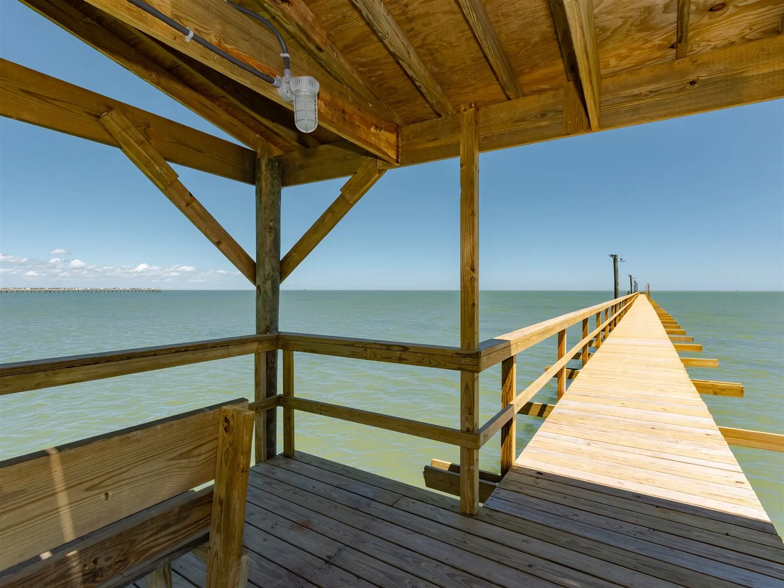 A wooden pier extends over the water beside a covered wooden platform.