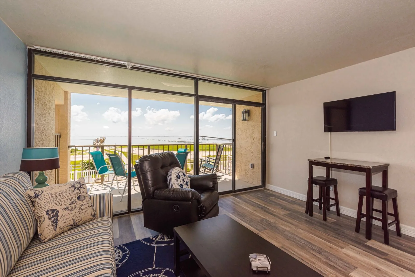 A living room opens onto a balcony, with seating and a wall-mounted television.
