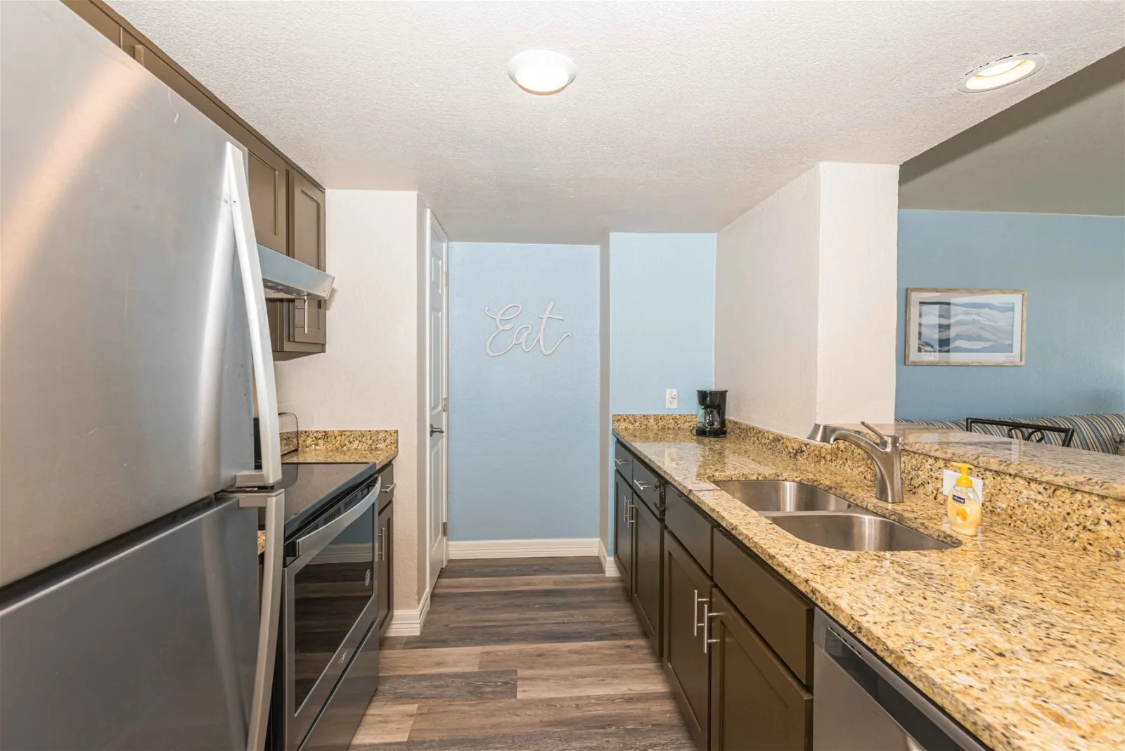 A kitchen with a long countertop, sink, and stainless-steel appliances.