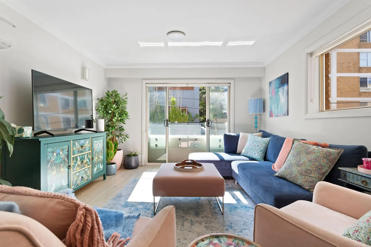 A bright living room has sliding glass doors opening onto a balcony.