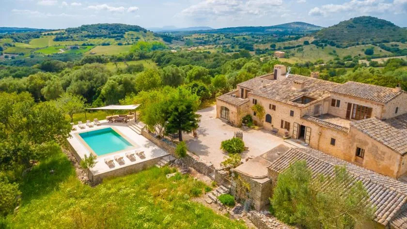 A countryside villa with a swimming pool sits among green rolling hills.
