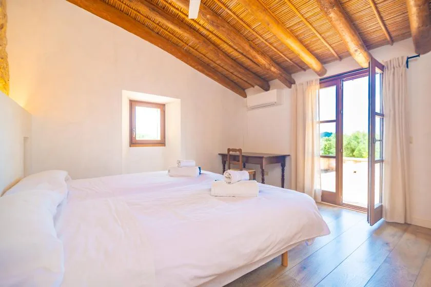 A bright bedroom with a large bed and open doors leading to a balcony.