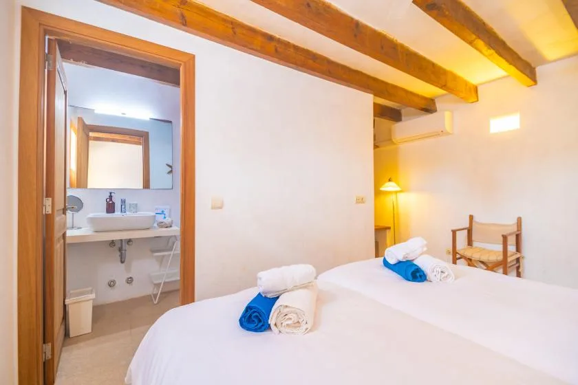 A bedroom with two beds and an open doorway to a bathroom.