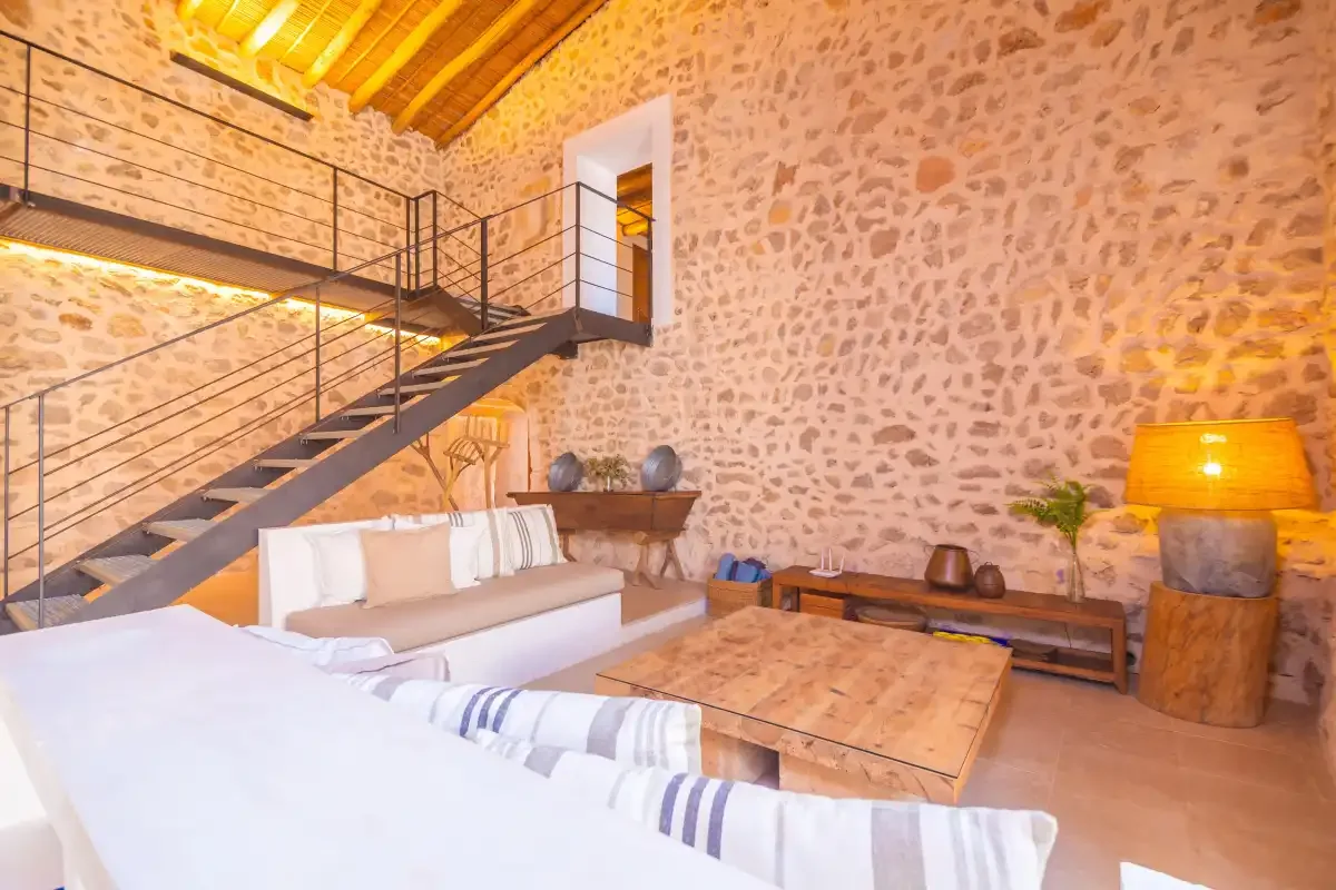 A stone-walled living room with a seating area beneath a staircase.