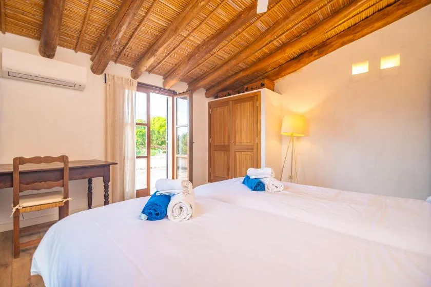 A bedroom with two beds and an open doorway to a garden.