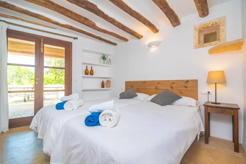 A bright bedroom with a large bed and exposed ceiling beams.