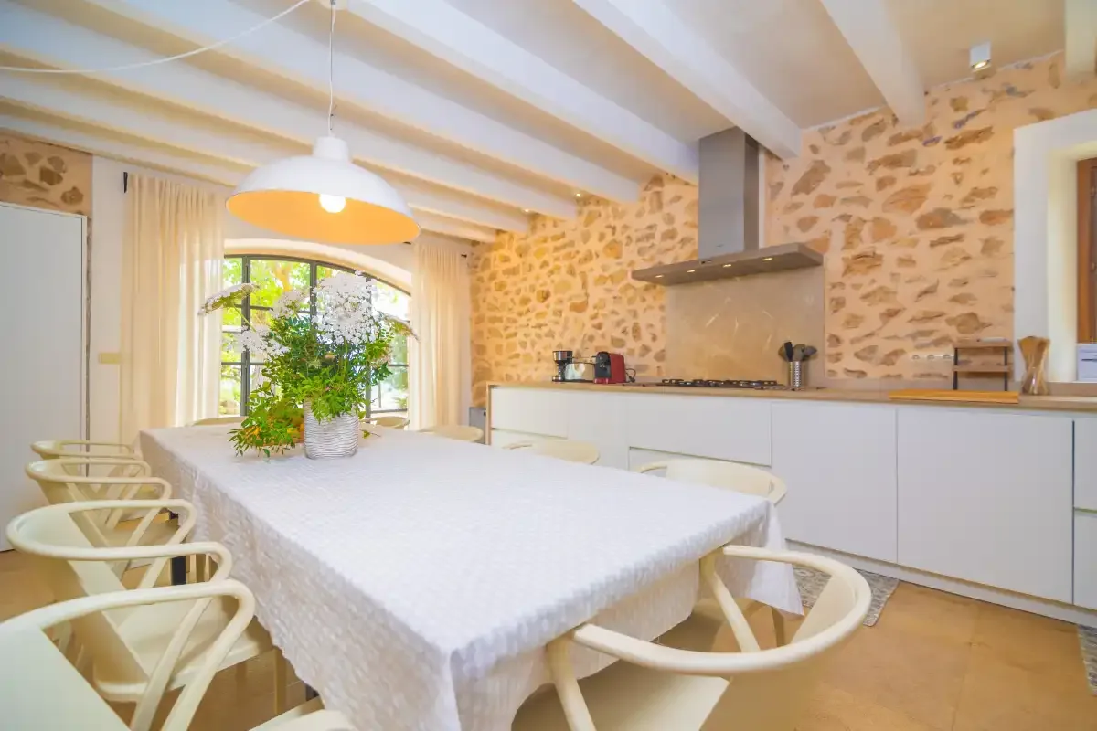 A bright kitchen and dining area with a large table and exposed stone walls.