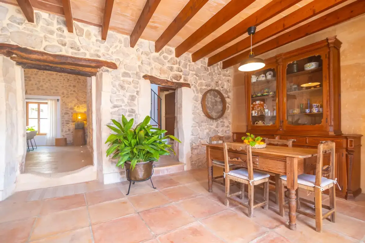 A rustic dining area with a wooden table, chairs, and a glass-front cabinet.