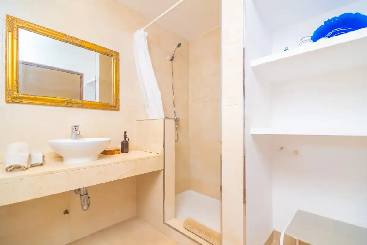 A bathroom with a sink, mirror, and shower.