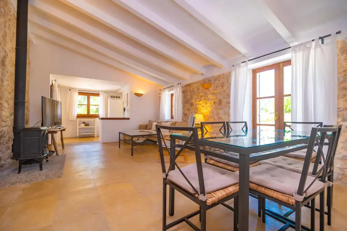 A bright dining and living area with a table, seating, and a television.