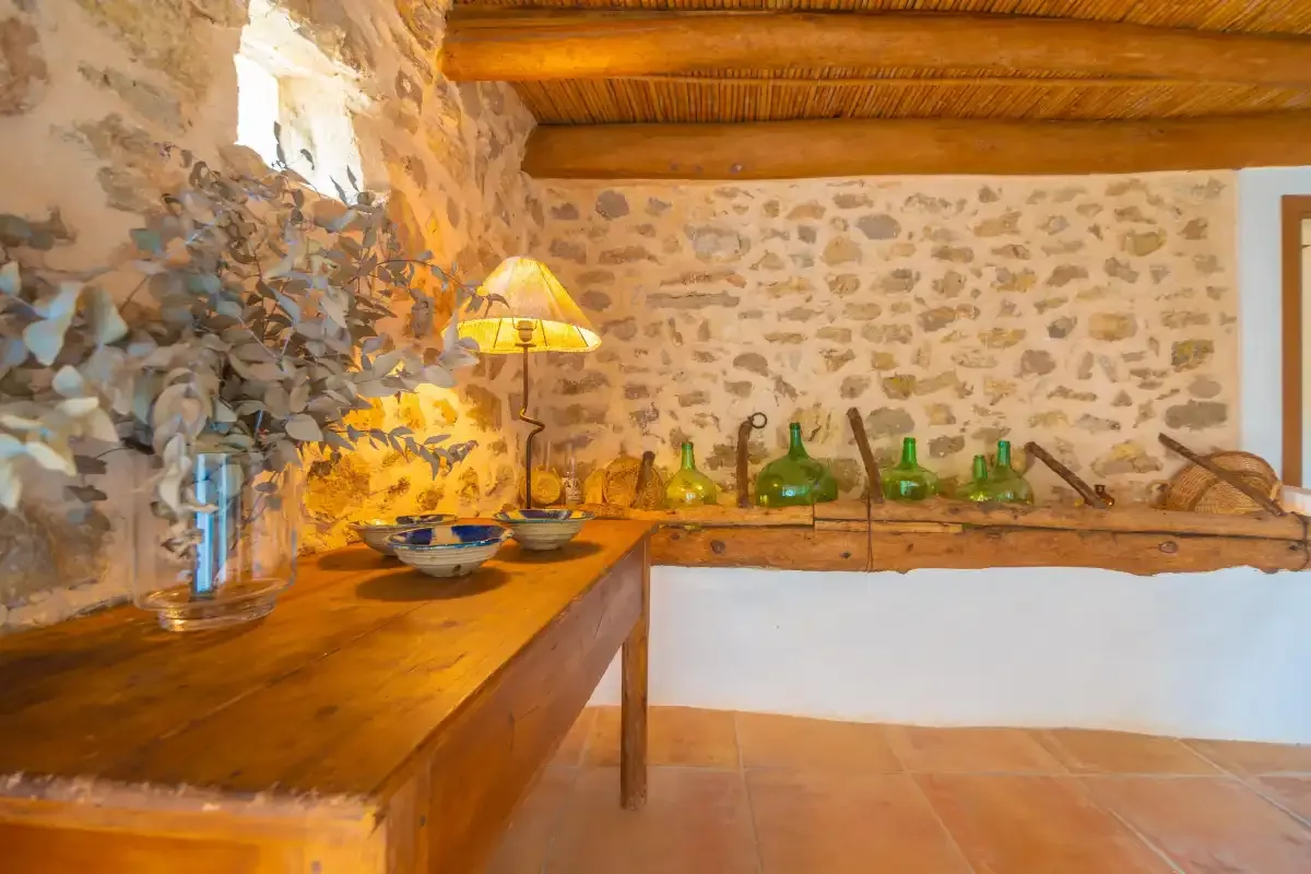 Rustic interior with a wooden counter beneath exposed stone walls.