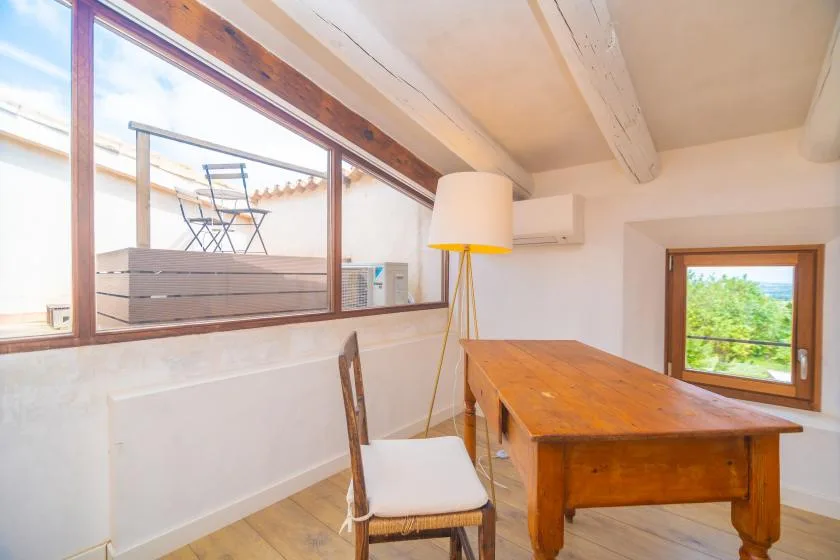 A bright room has a wooden table beside a large interior window.