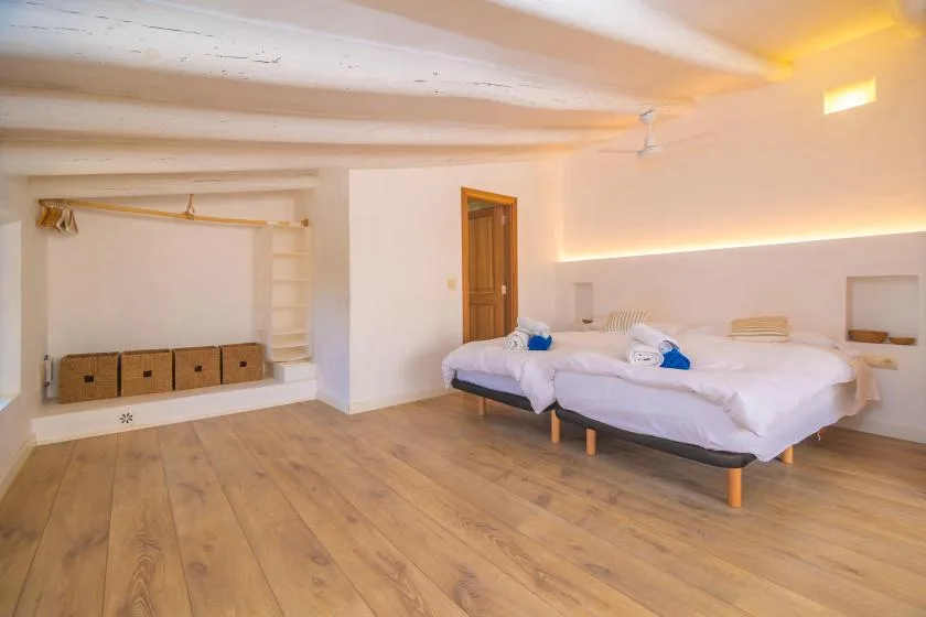 A bedroom with a bed, wooden flooring, and built-in shelving.