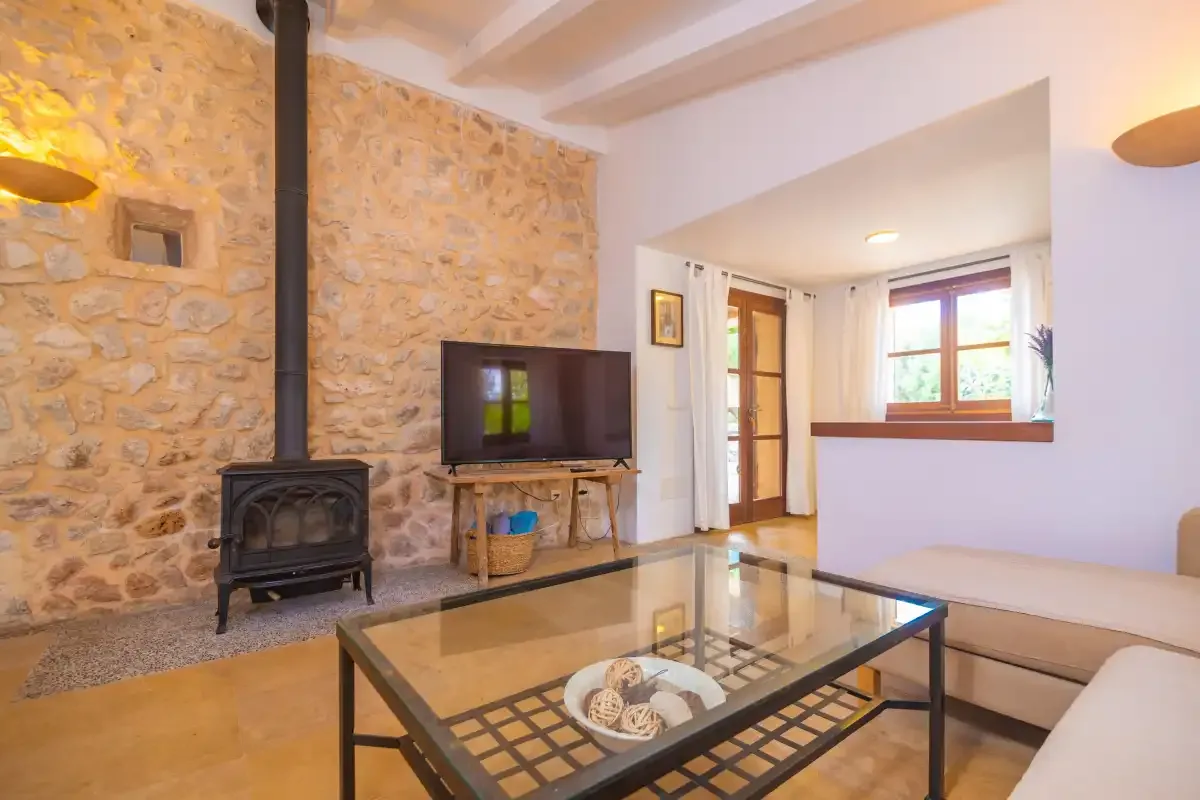 Living room with stone wall, television, and glass coffee table.