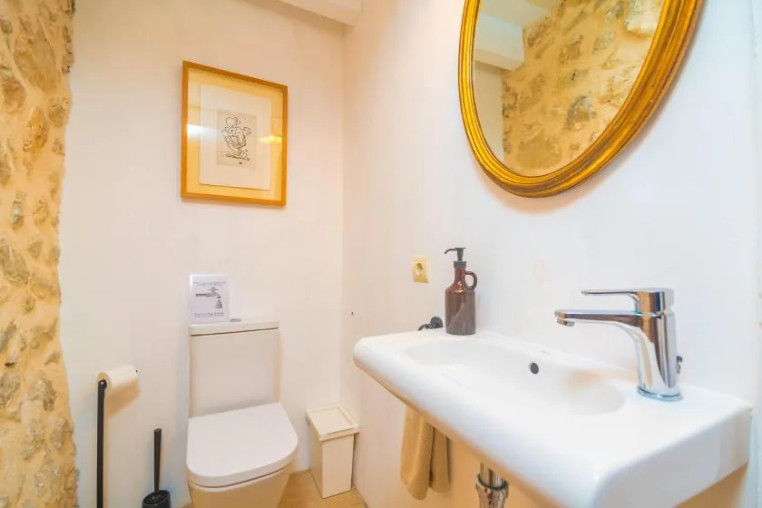 A compact bathroom with a toilet, wall-mounted sink, and round mirror.