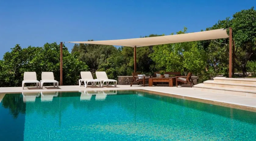 An outdoor swimming pool with lounge seating and a shaded dining area.