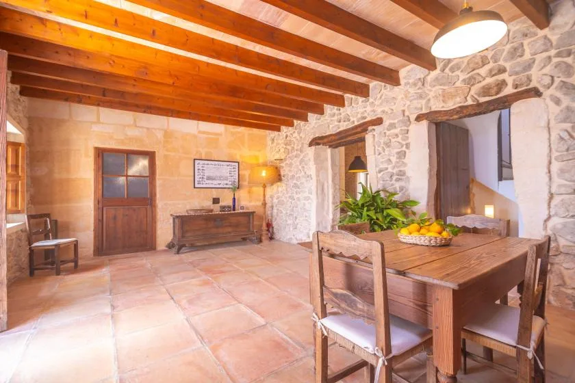 A rustic stone dining room with a wooden table beneath exposed ceiling beams.