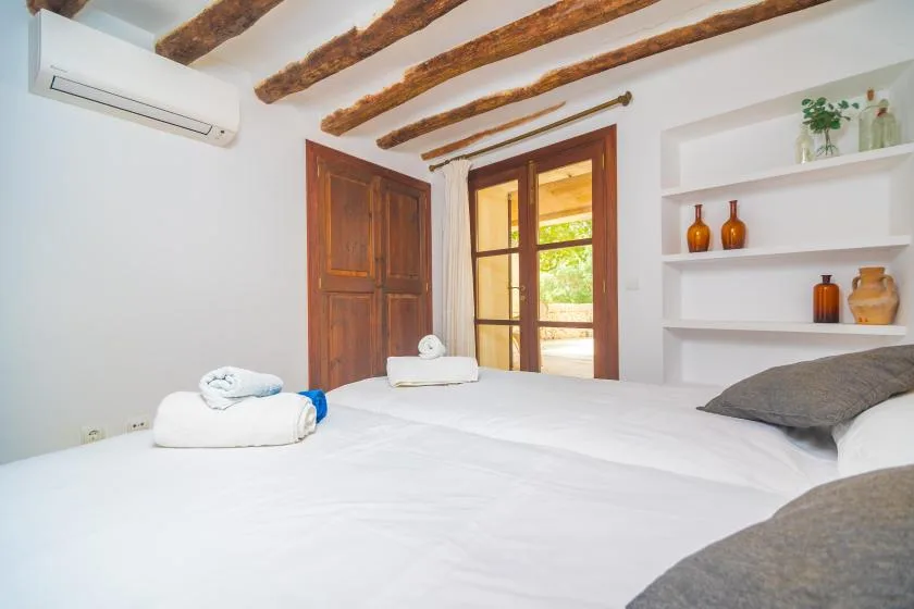 A bright bedroom with a neatly made bed and open wooden doorway.