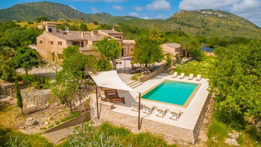 A hillside property with a turquoise swimming pool and surrounding green hills.