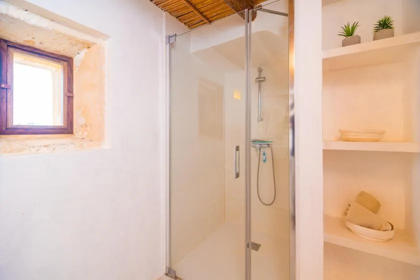 A bathroom with a glass-enclosed shower and built-in shelves.