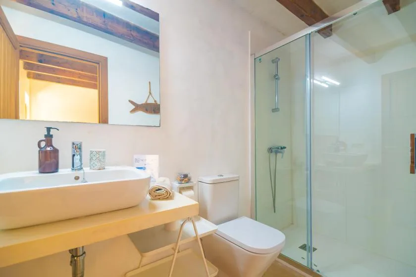A bright bathroom with a sink, toilet, and glass shower.