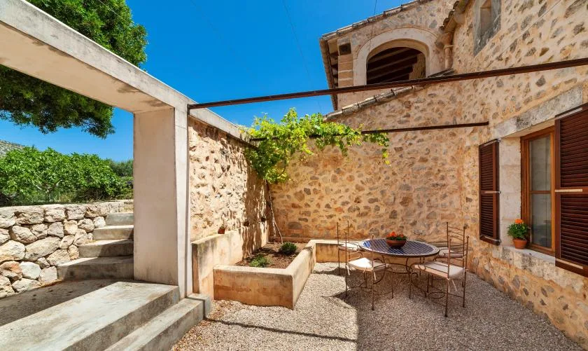 A stone courtyard with a round outdoor table and climbing greenery.