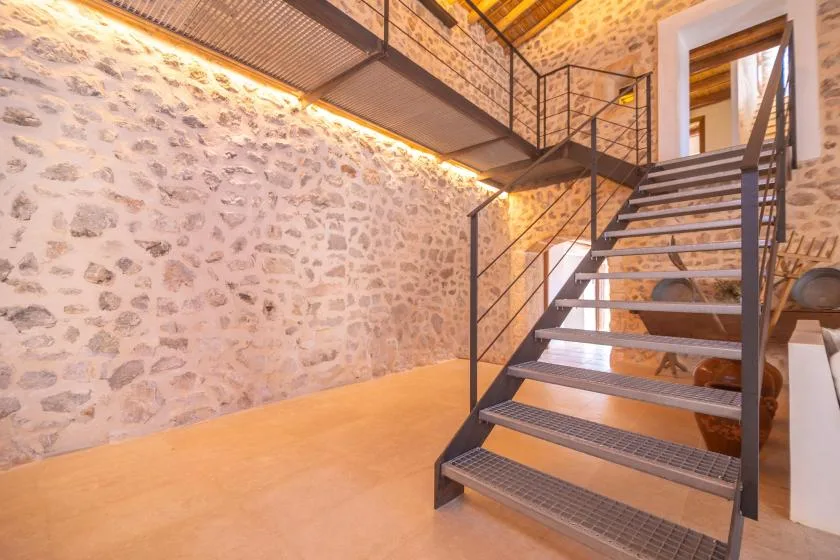 A stone-walled interior with an open staircase leading to an upper level.