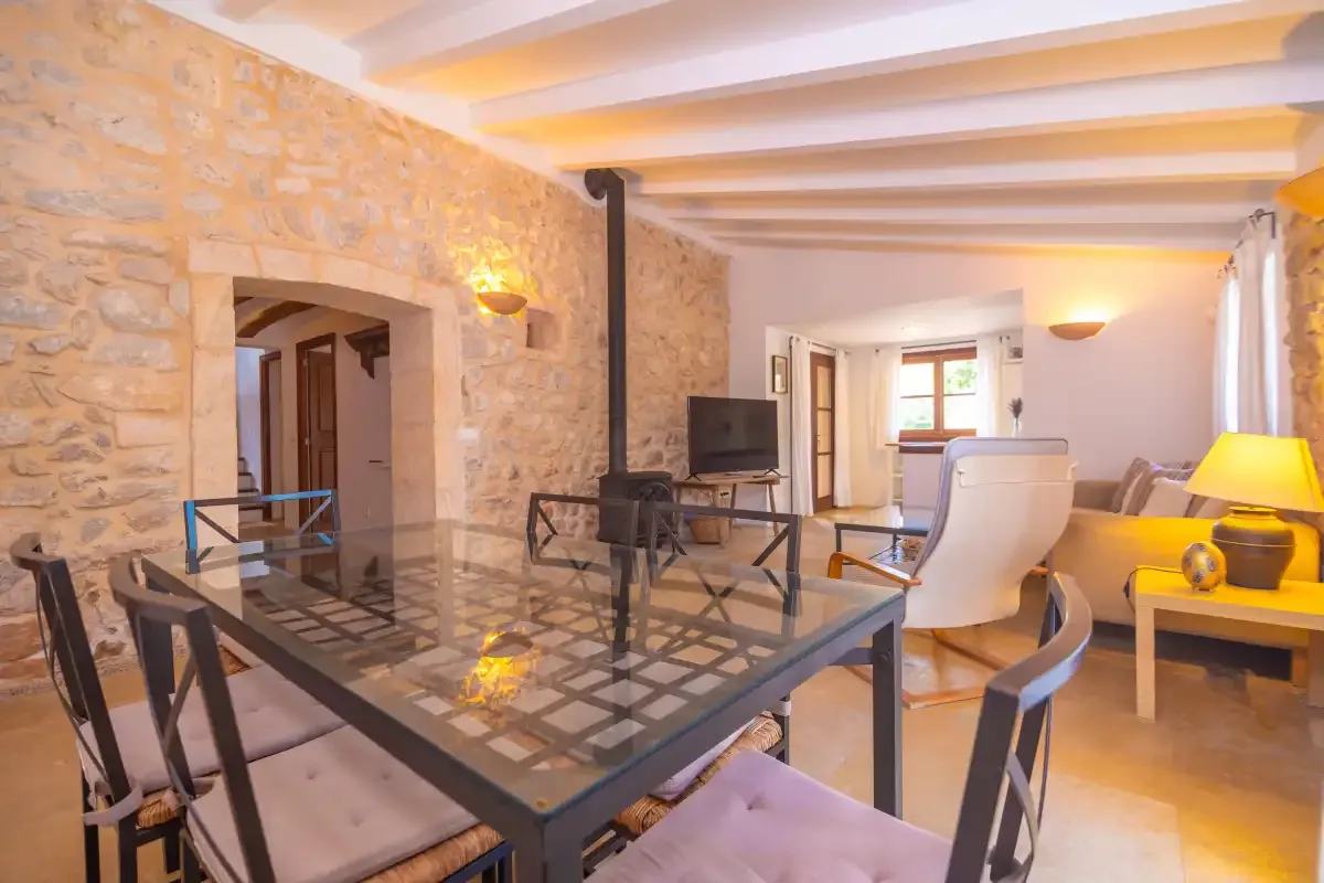 A dining area with a glass-top table and seating beside a stone wall.