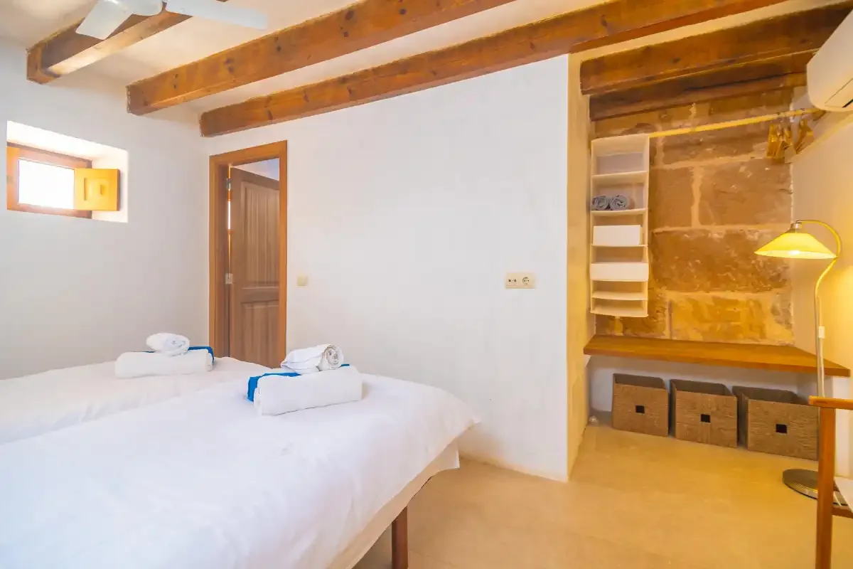 A bedroom with white bedding and an open storage nook.