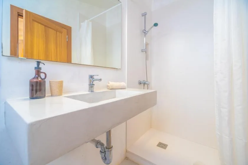 A bright bathroom with a wide sink and a shower.