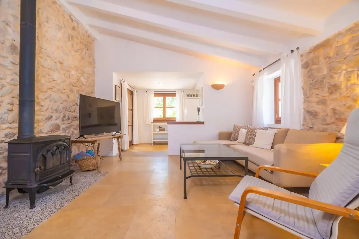 A living room with seating, a television, and a freestanding stove.