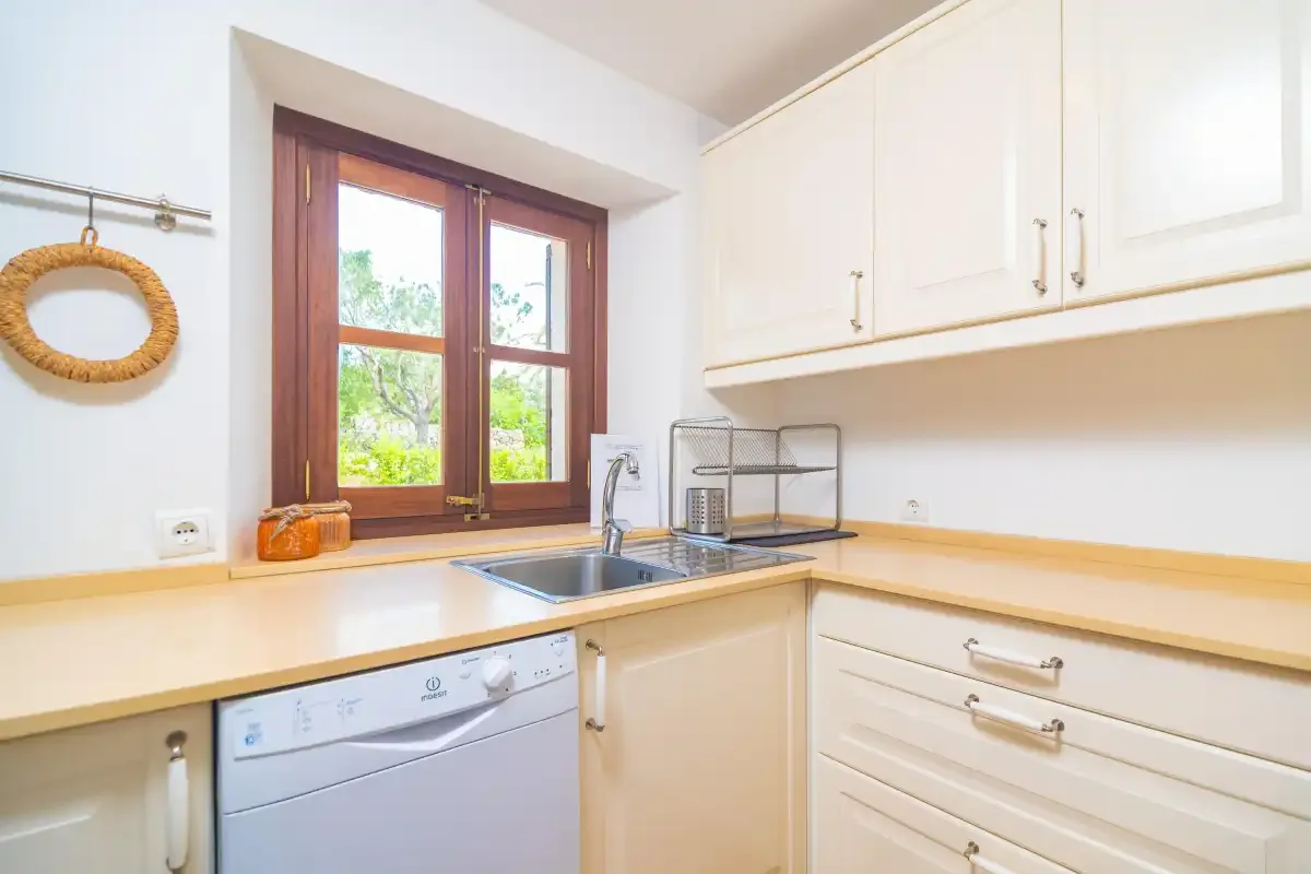 A bright kitchen with a sink beneath a window and white cabinets.