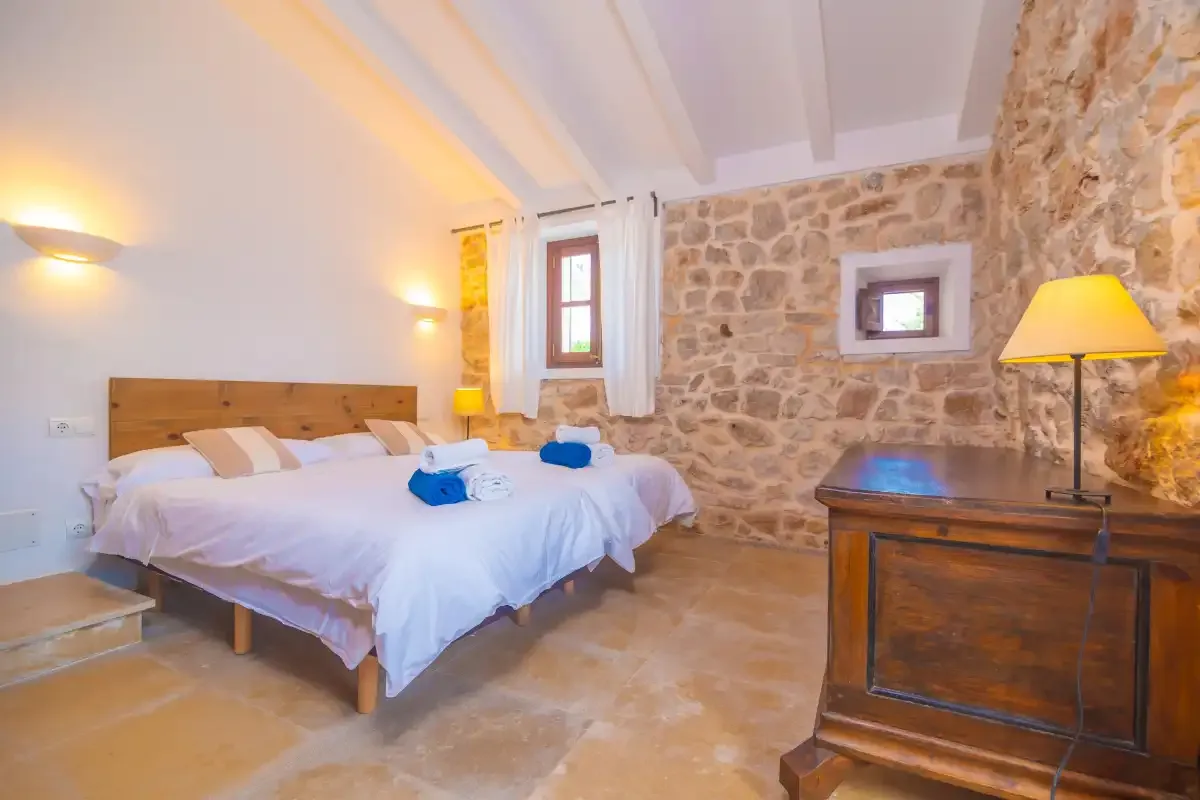 A bedroom with a bed beside an exposed stone wall.