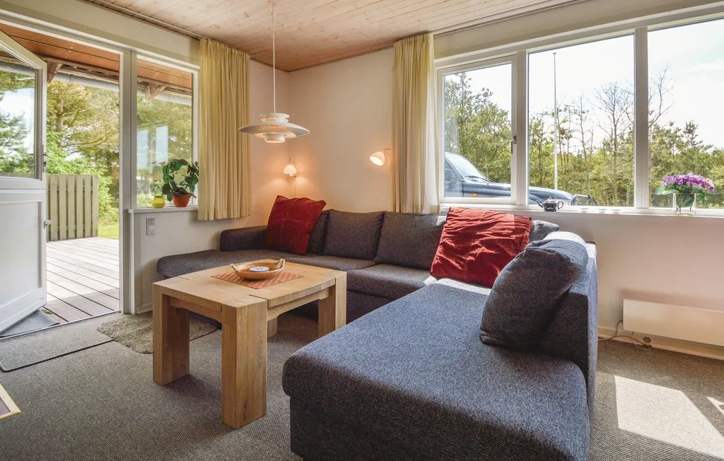 A living room with a sectional sofa, coffee table, and large windows.