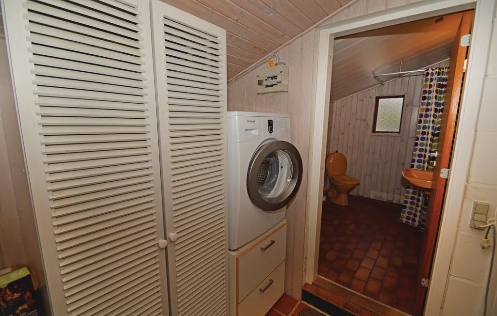 A laundry area opens into a bathroom with a toilet and shower curtain.