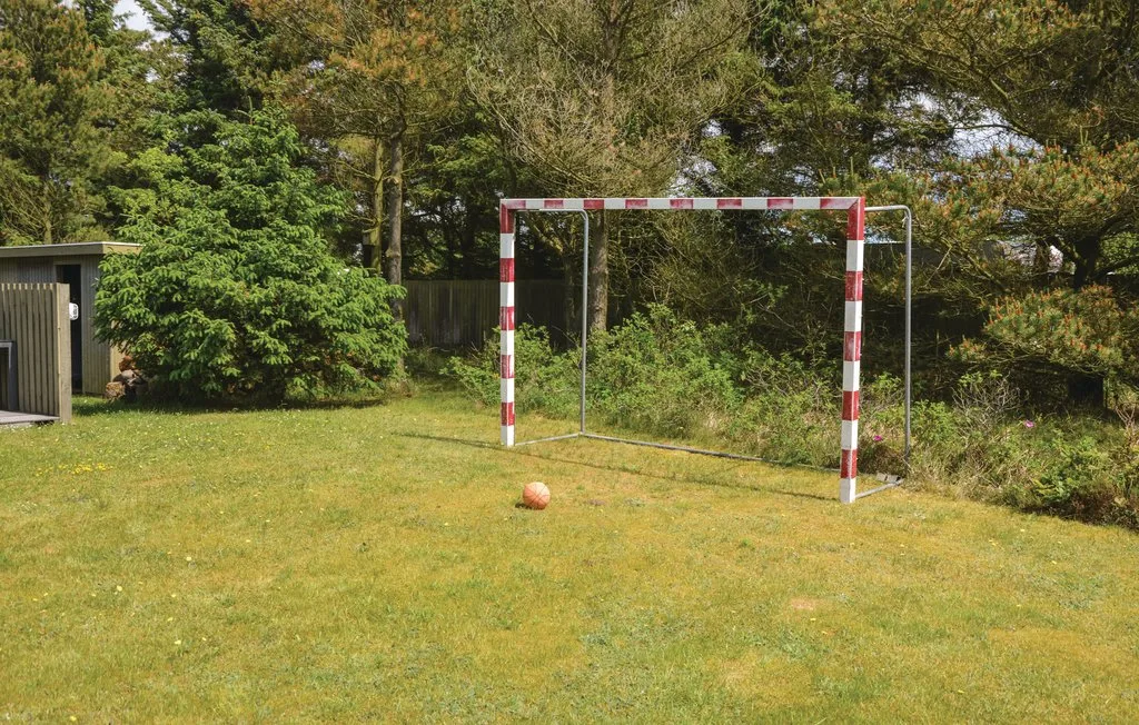 A grassy outdoor play area with a soccer goal and ball.