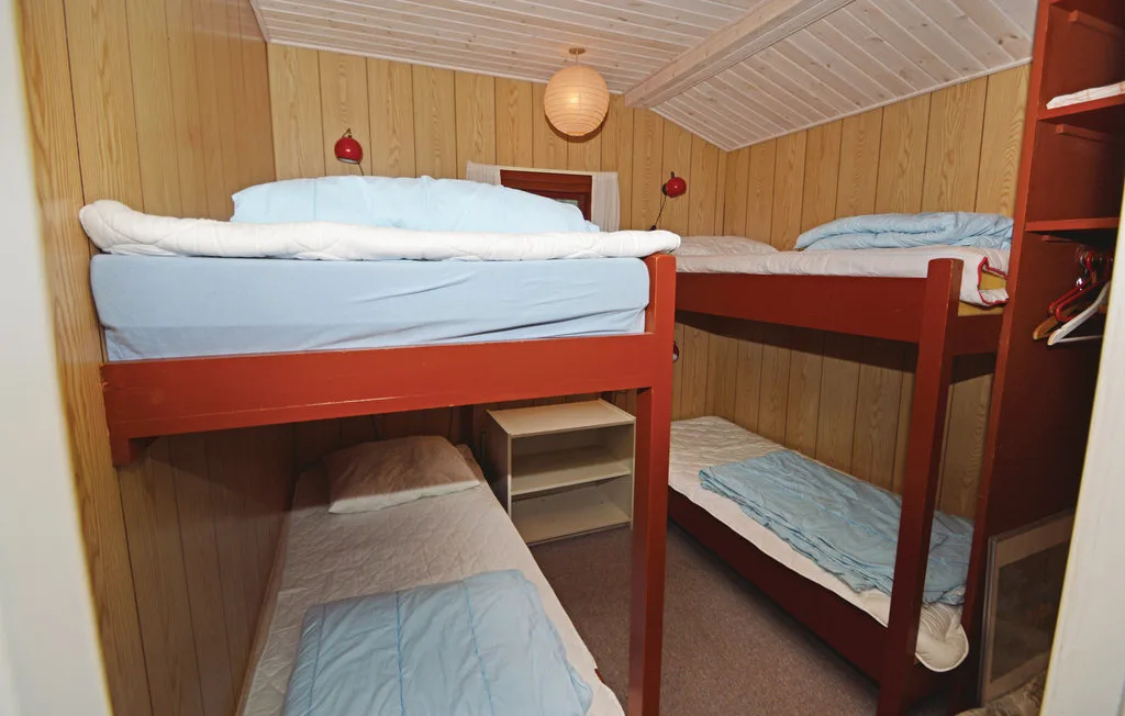 A compact sleeping room with wooden bunk beds and pale bedding.