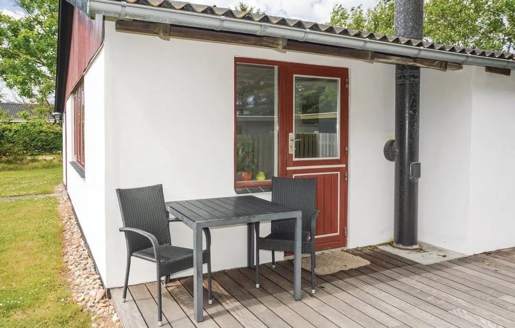 An outdoor patio with a table and seating beside a red door.