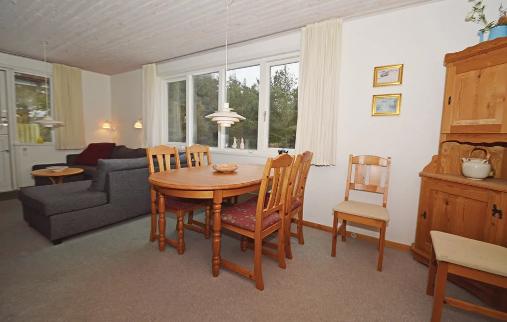 A living and dining area with a wooden table, chairs, and a gray sofa.