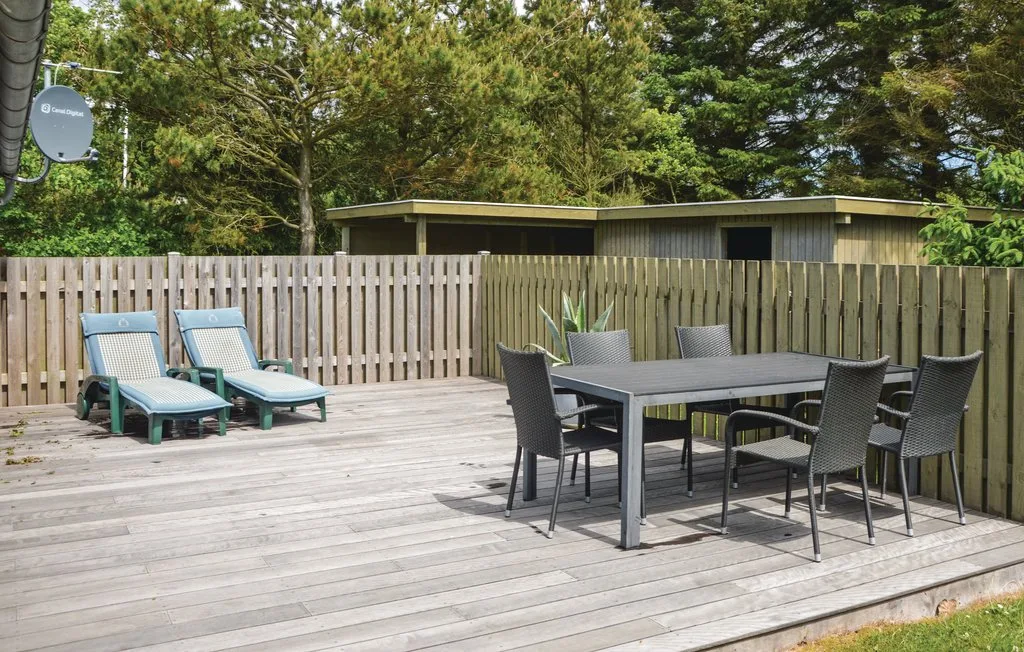 An outdoor deck has a dining table and seating beside two lounge chairs.