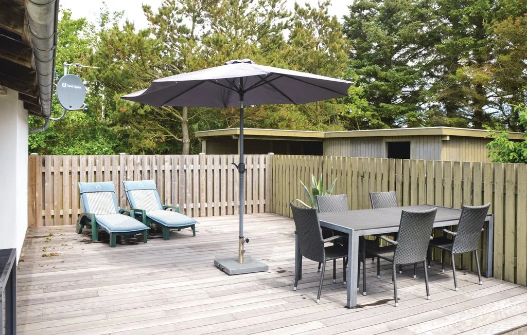 An outdoor wooden deck with lounge seating and a dining table beneath an umbrella.