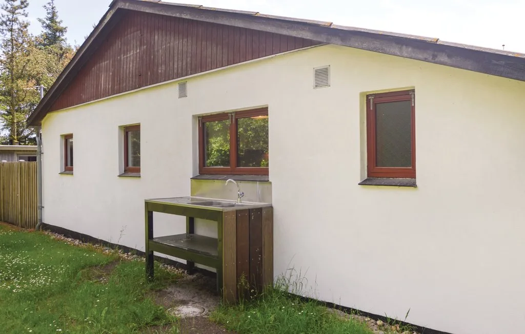 A small white building with brown-trimmed windows and an outdoor sink.