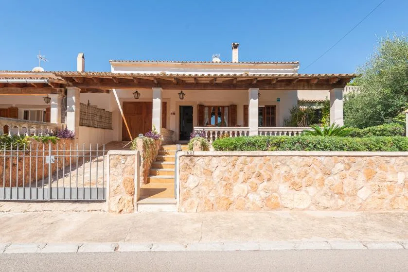 A single-story house with a covered front porch and stone boundary wall.