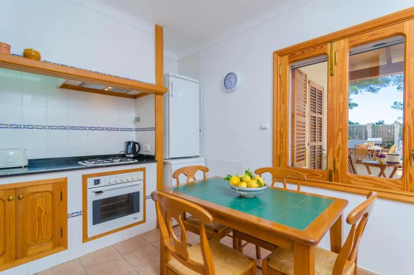 A bright kitchen and dining area with a wooden table beside a large window.