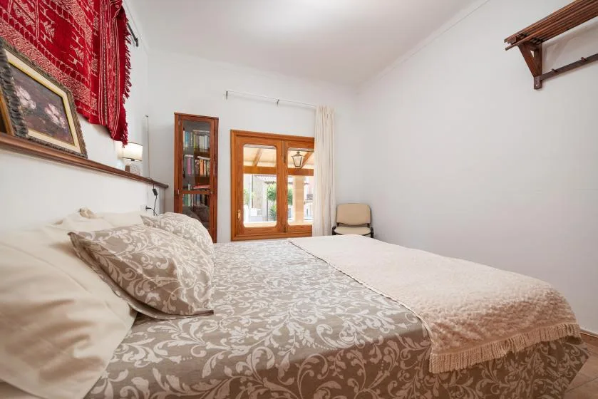 A bedroom with a patterned bedspread and a window.