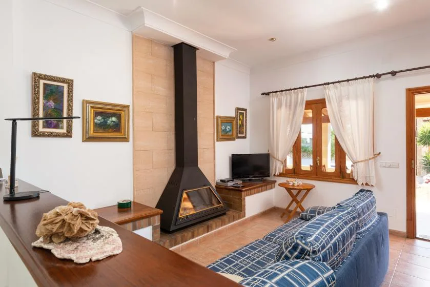 A living room with a fireplace, a television, and seating by the window.