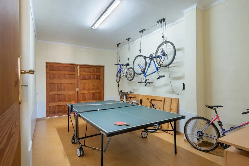 A recreation room with a ping-pong table and bicycles hanging on the wall.