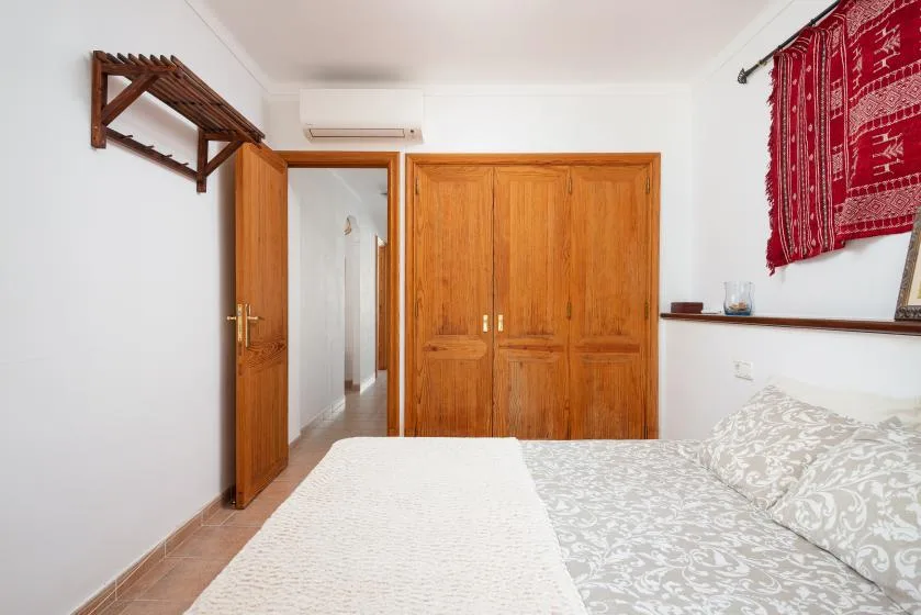 A bedroom with a wooden wardrobe and patterned bedding.